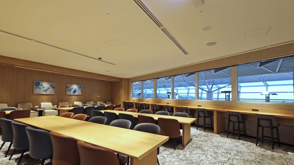 A conference room with long tables and chairs, large windows, and wooden paneling. 5
