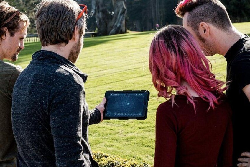 A group of people outdoors, one holding a tablet. 4