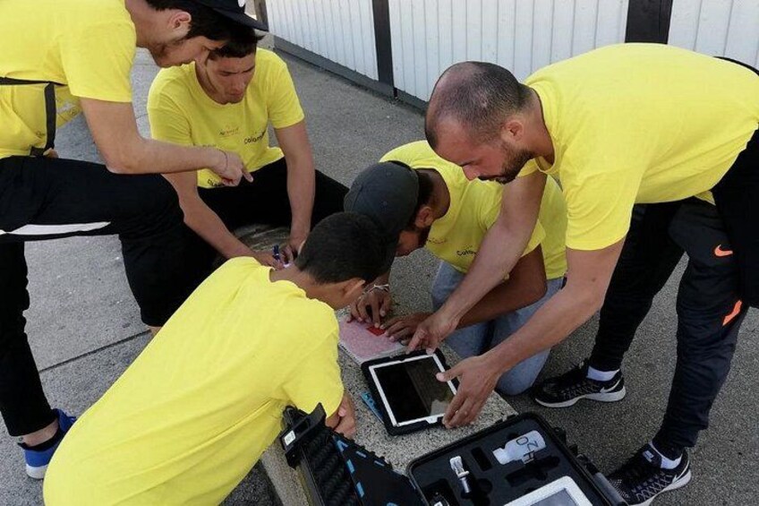 A group of people in yellow shirts gathered around a table with a tablet and a camera. 5