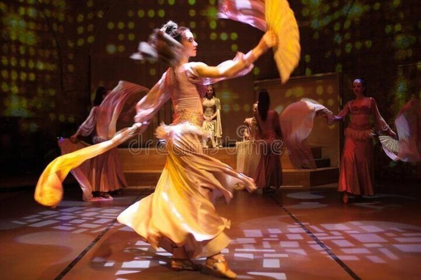 A dancer in a yellow dress performing with a fan. 1