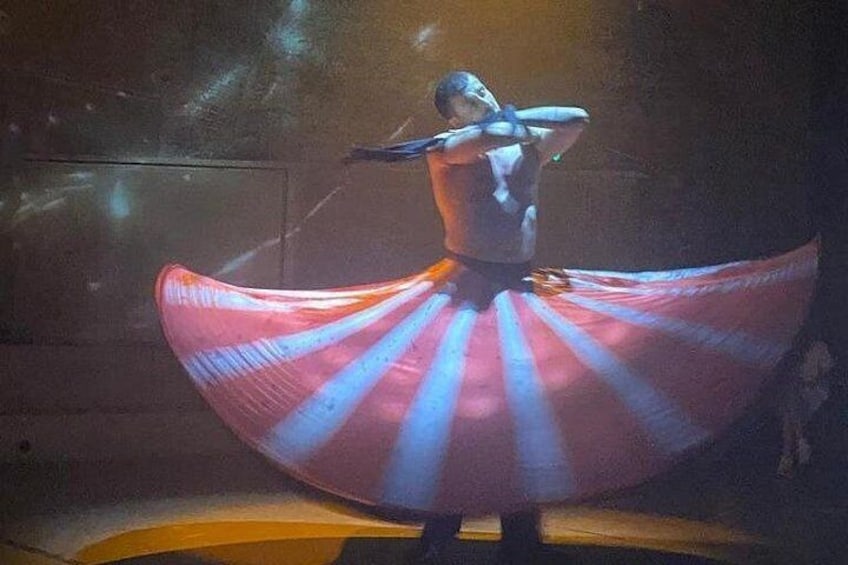 A person in a flowing, multicolored skirt performing on stage. 4