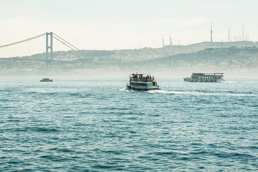 A ferry in the water with a bridge in the background. 5