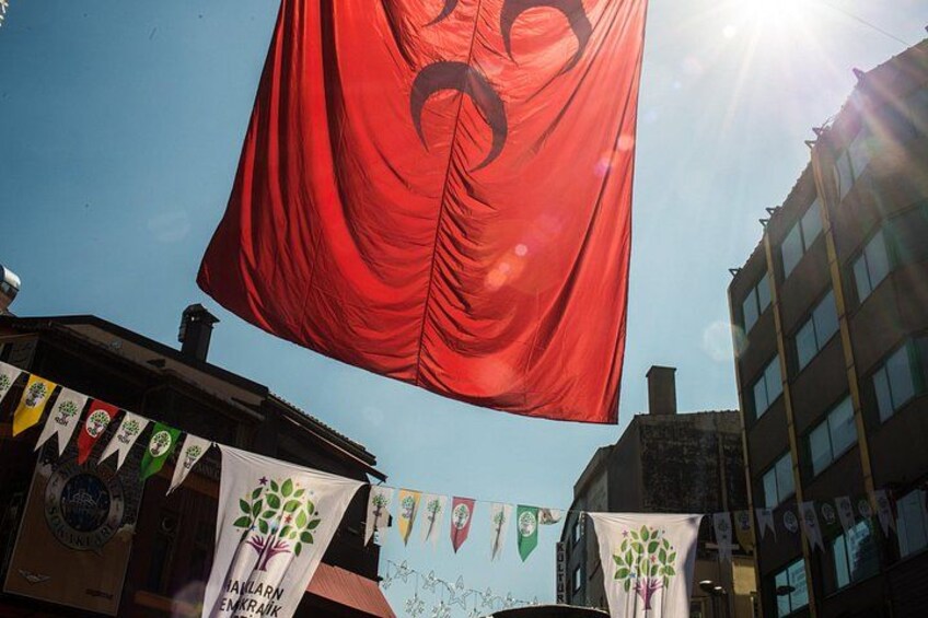 A red flag with a black symbol, buildings, and a clear sky. 4