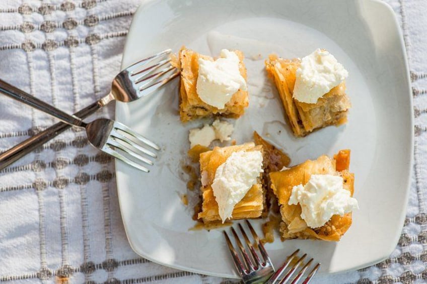 A plate with pieces of pie topped with whipped cream, accompanied by forks. 4
