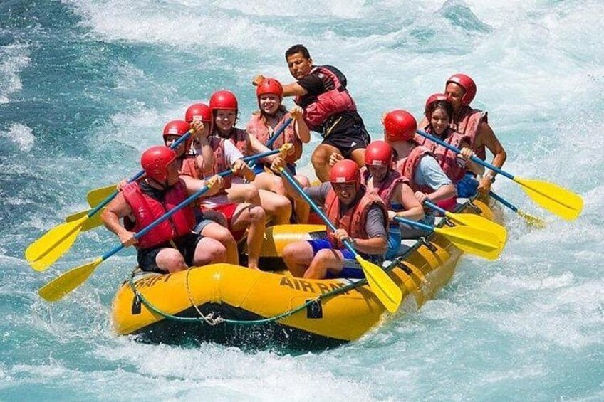 A group of people in a yellow inflatable raft with paddles, navigating through a river. 1