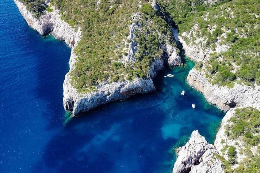 A coastal landscape with rocky cliffs, clear blue waters, and sparse vegetation. 2