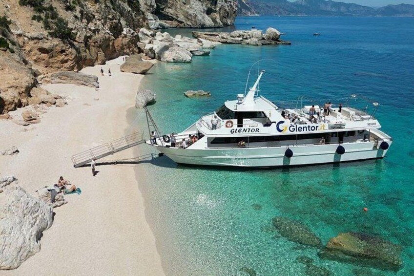 A boat named 'Glentor' docked at a beach with clear turquoise water and rocky formations. 4