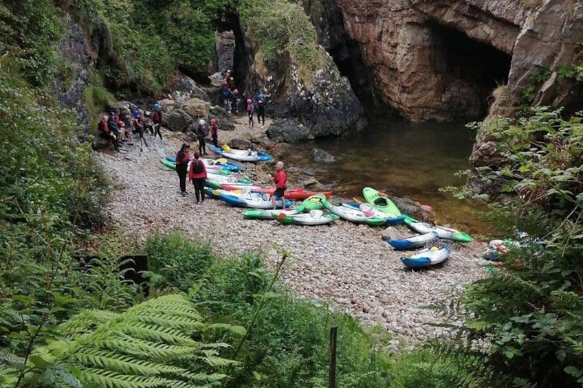 Un grupo de personas en una costa rocosa con kayaks alineados. 1