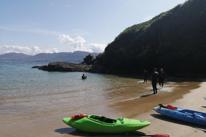 Una playa con kayak, una persona en kayak, y gente caminando por la orilla. 3