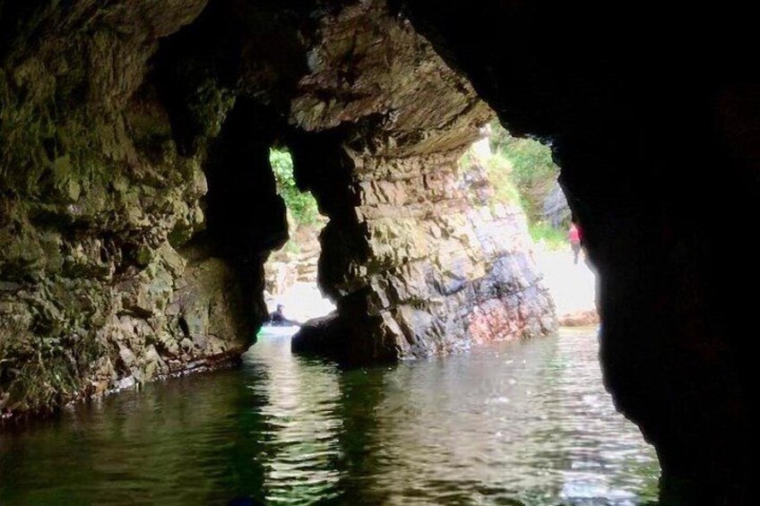 A cave with water inside, a rock formation, and a person in the distance. 4