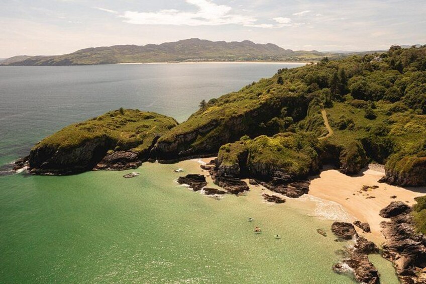 A coastal landscape with a sandy beach, rocky outcrops, and a clear view of the sea. 3