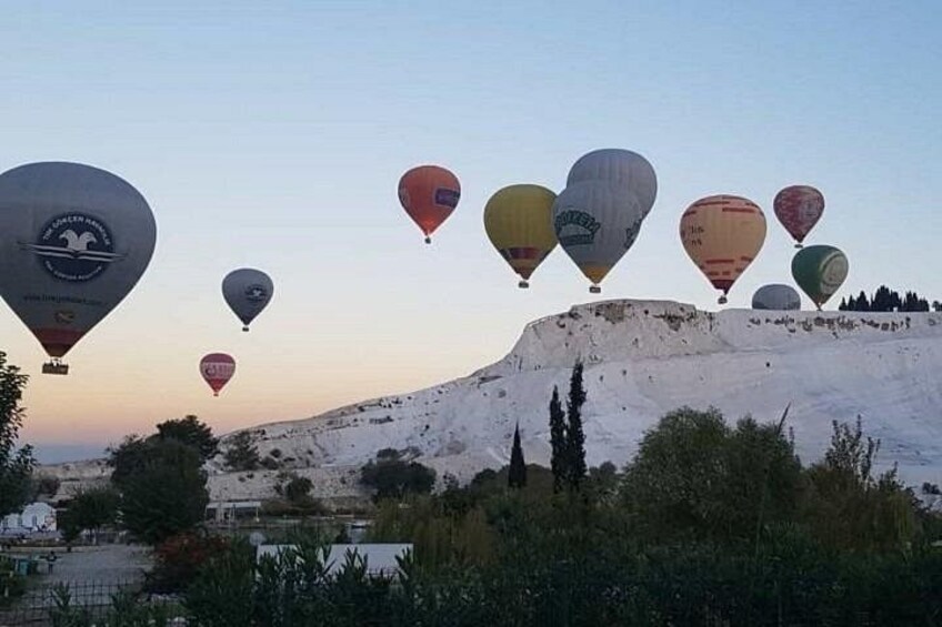 Een groep luchtballonnen boven een besneeuwd landschap, met een heuvel op de achtergrond. 4