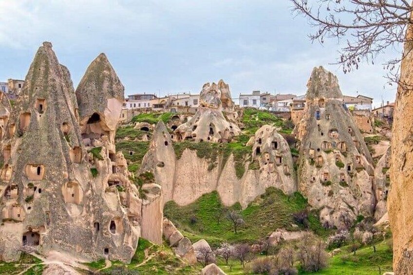 A landscape with unique rock formations, some with holes, and a village in the background. 5