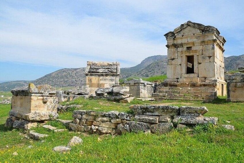 Ancient ruins with stone structures and steps, set against a mountainous backdrop. 4