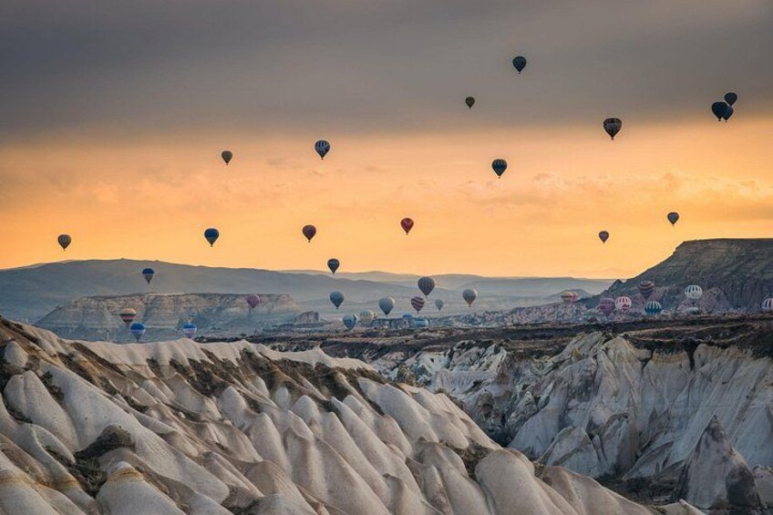 Eine Landschaft mit weißen Felsformationen und Heißluftballons am Himmel. 2
