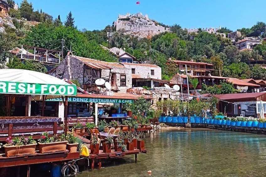 Un restaurante frente al agua llamado 'Fresh Food' con terraza, un muelle y un fondo de colinas y edificios. 4