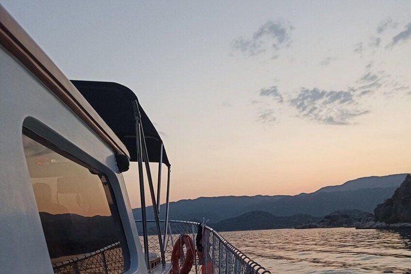 Un bote con toldo negro, un flotador salvavidas y vista a las montañas y al agua durante el atardecer. 2