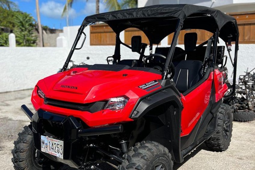 A red Honda ATV with a black canopy, large tires, and a license plate. 3