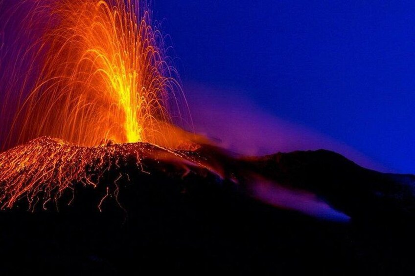 Ein Vulkan, aus dem Lava ausbricht, mit leuchtendem Glutmeer und Rauch. 1