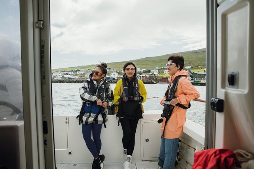 Three people on a boat with a coastal landscape in the background. 3