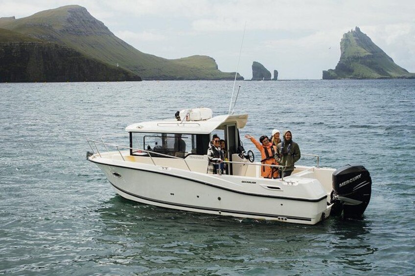 A white motorboat with a Mercury outboard on calm water, surrounded by a rocky coastline with hills in the background. 2