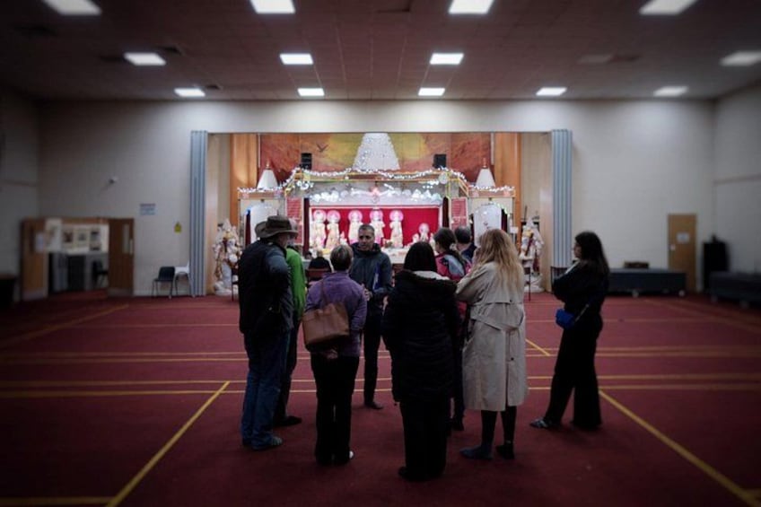 A group of people gathered in a hall with a decorated altar at the front. 3