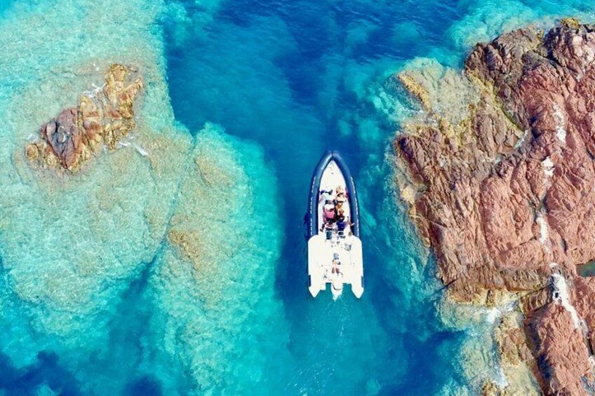 A boat on clear turquoise water near rocky formations. 1