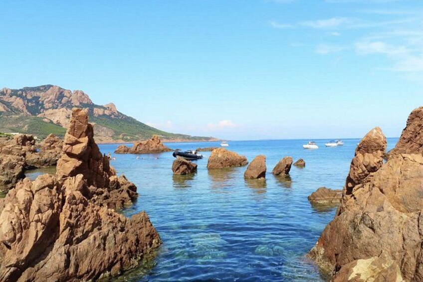 A rocky coastline with clear blue water, boats, and mountains in the background. 2