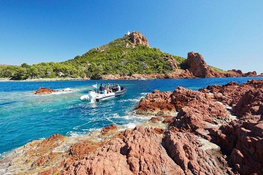 A boat on a rocky coastline with clear blue water and a hill in the background. 3