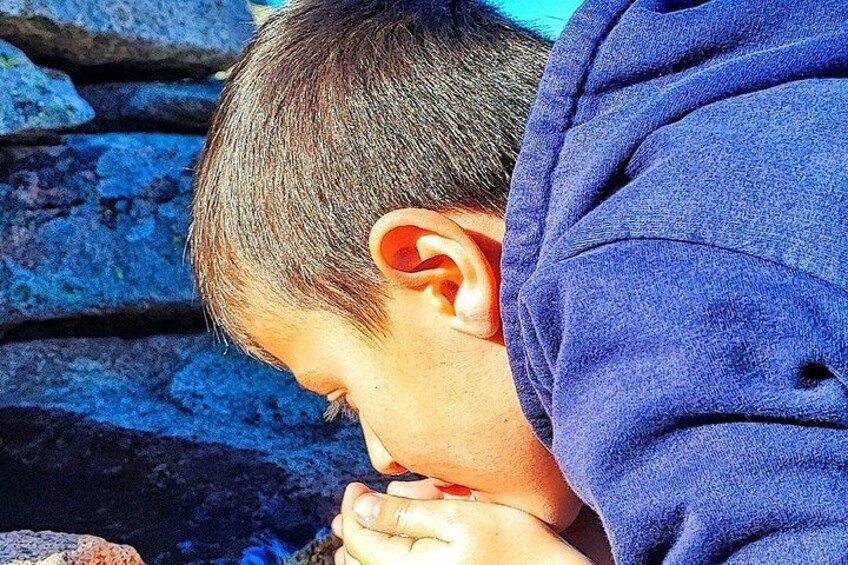 A person with their head down, wearing a blue garment, against a background of stone steps. 3