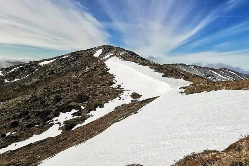 A snow-covered mountain slope with rocky terrain and a clear sky. 2
