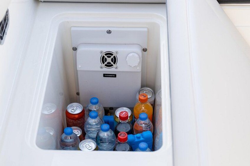 Een witte ruimte met een waterpomp, gevuld met verschillende flessen en blikjes. 5
