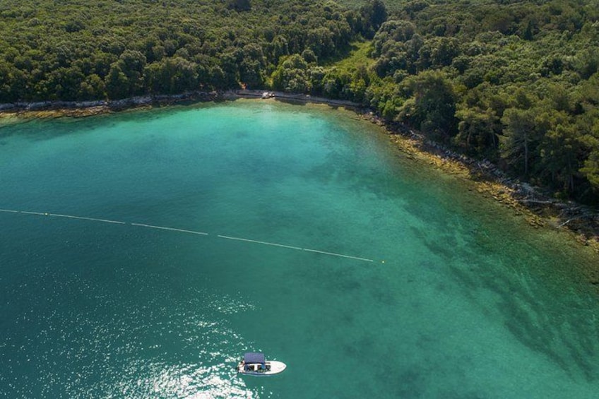 Een boot op een turquoise zee, omringd door een dichtgroene bos. 2