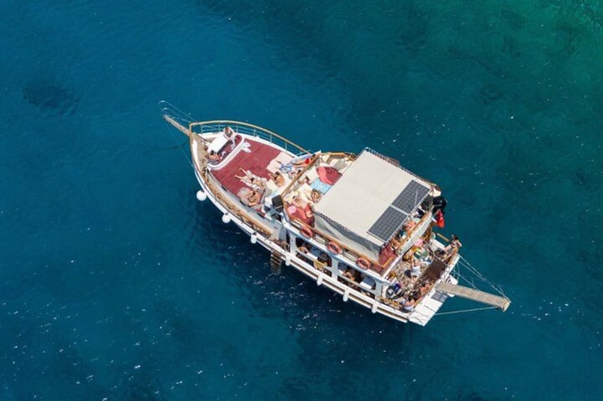 A boat with multiple decks and passengers, floating on clear blue water. 4