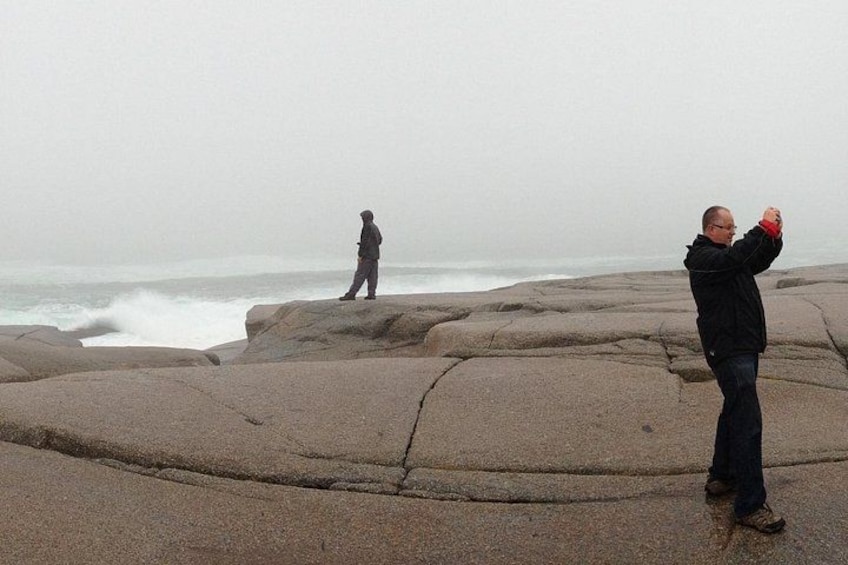 Two people on rocky terrain near a body of water. 1