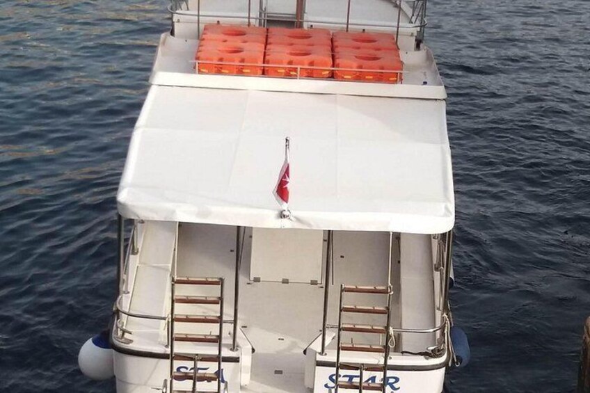 A boat with a white cabin, a red flag, and orange life jackets on the deck. 5