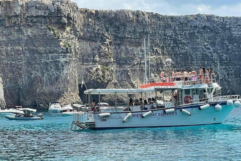 A boat named 'MIEMO' with passengers, docked near a rocky cliff. 2