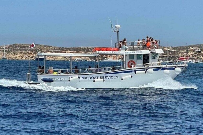 A white boat with 'EMA Boat Services' written on the side, moving on the water with a rocky coastline in the background. 2