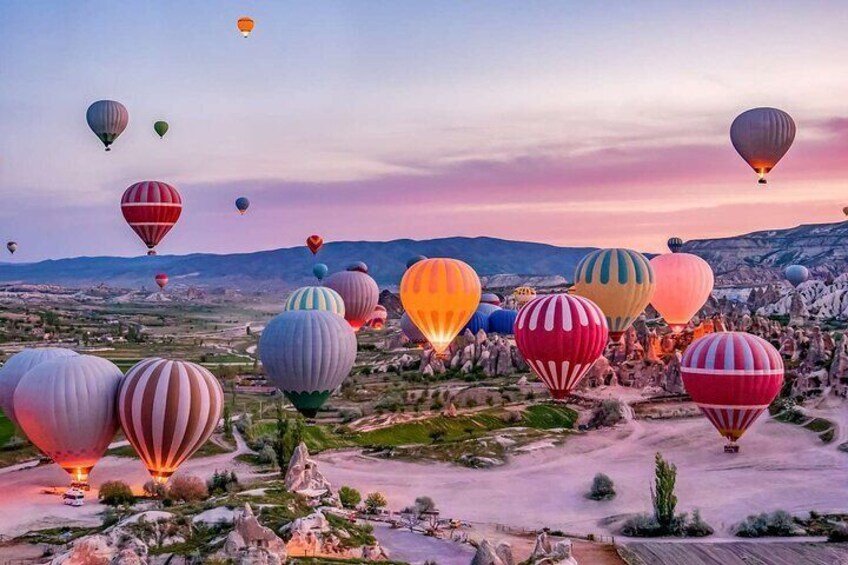 Paesaggio con numerosi palloni aerostatici colorati e terreno roccioso. 1