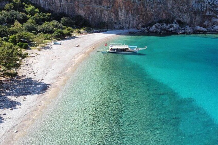 A boat on a turquoise beach with clear water and rocky cliffs. 3