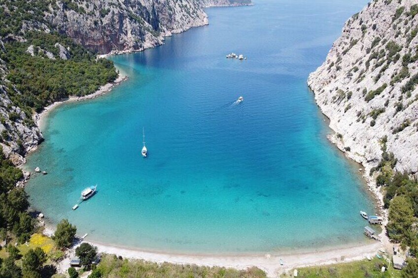 A coastal landscape with clear turquoise waters, boats, and rocky cliffs. 5