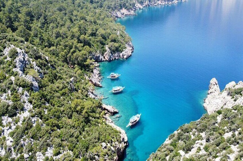 A coastal area with clear turquoise waters, rocky cliffs, and dense green vegetation. 2