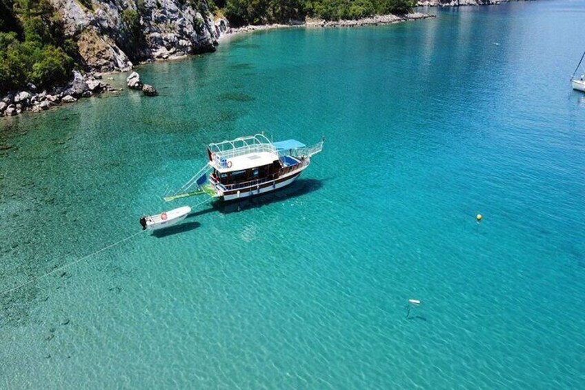 A boat anchored in clear turquoise water near rocky shores. 4