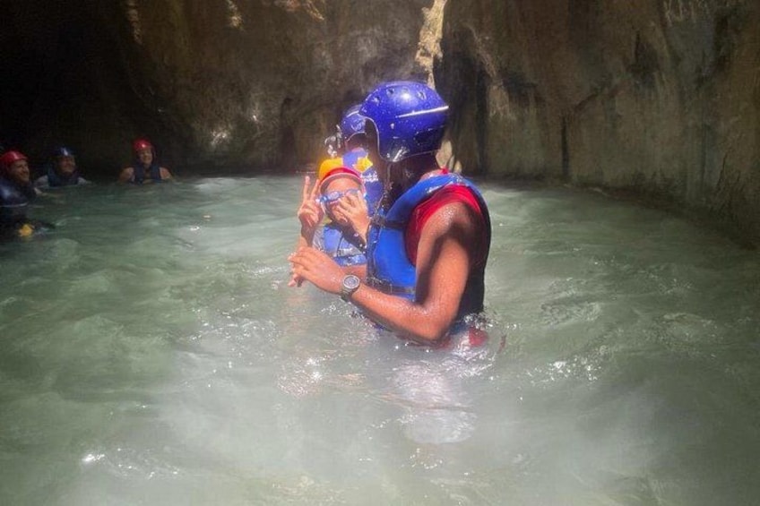 A person in a cave with water, wearing a helmet and life jacket. 4