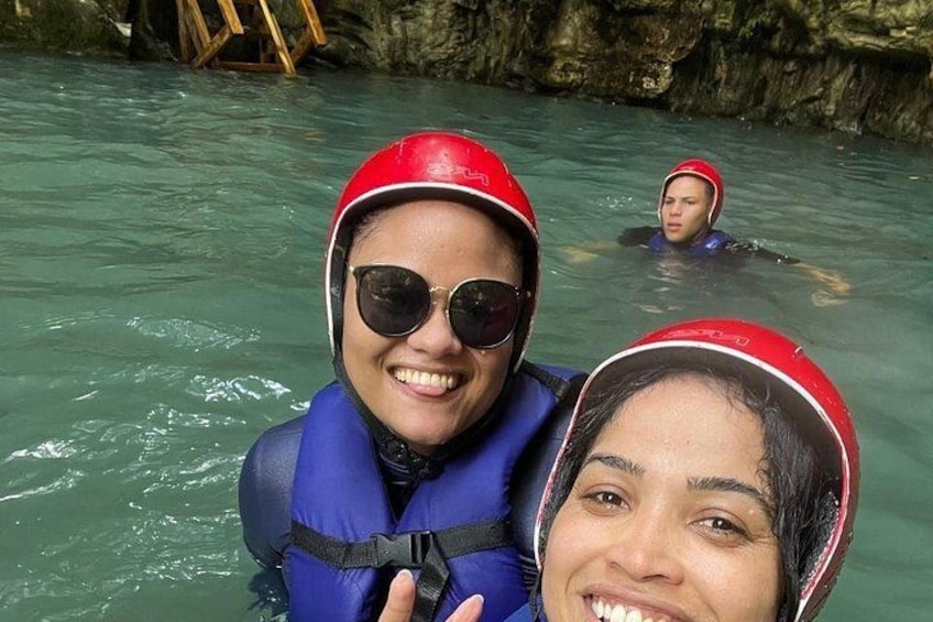 Two people in a river wearing helmets and life jackets. 5