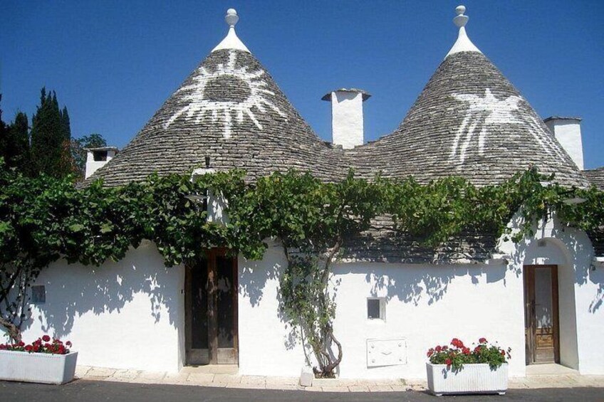 A white building with a conical roof, a door, and a window. 2