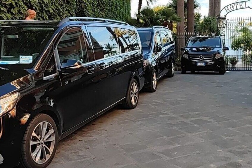 A black limousine parked in front of a gated entrance with a sign that reads 'HOTEL.' 3