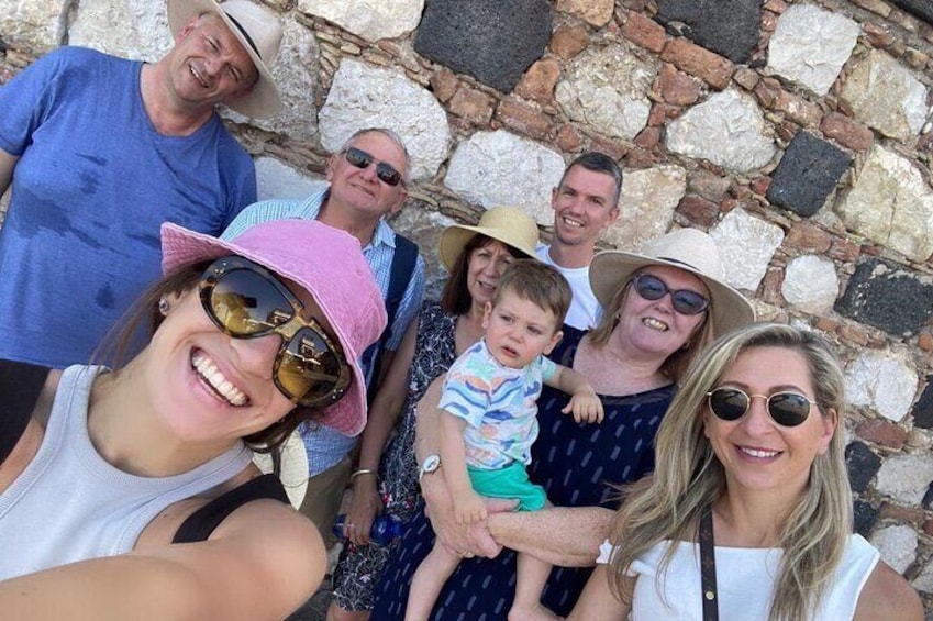 A group of people standing in front of a stone wall. 1