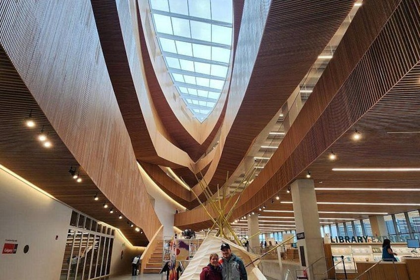 A modern interior with a central skylight, wooden beams, and a staircase. 3