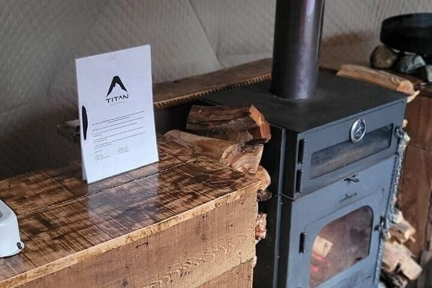 Un poêle à bois, avec une plaque portant l’inscription « TITAN », est posé sur une table en bois. 4